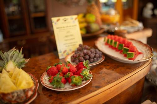 a buffet with plates of fruit on a table at Araucária Lodge - 800 metros do Capivari in Campos do Jordão