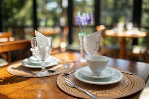 a wooden table with two glasses and a cup on it at Araucária Lodge - 800 metros do Capivari in Campos do Jordão