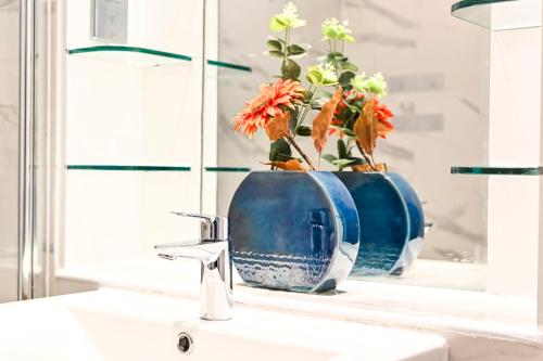 a bathroom sink with a blue vase with flowers in it at Stunning 3 Bed Central London Apartment in London