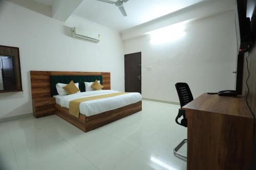 a bedroom with a bed and a desk and a television at Hotel Classic Crown in Jaipur