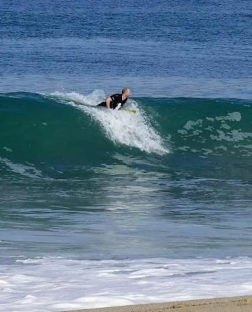 a man riding a wave on a surfboard in the ocean at Sirena's Beach & Surf Club in Canoa
