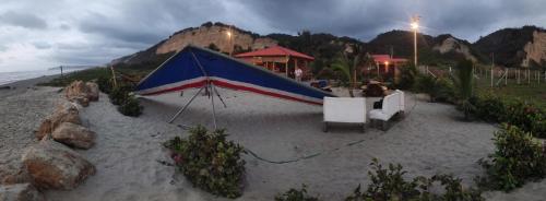 a tent on the beach with a person sitting in a chair at Sirena's Beach & Surf Club in Canoa