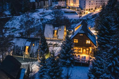 a house with lights on in the snow at night at Kežman Mountain Houses in Kopaonik
