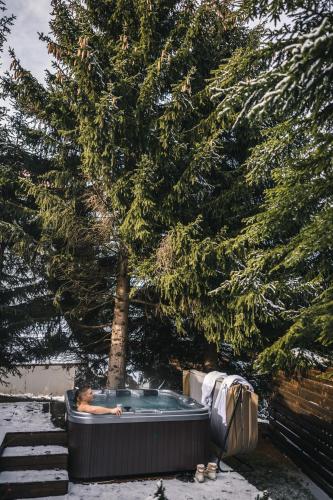 a person in a hot tub under a tree at Kežman Mountain Houses in Kopaonik