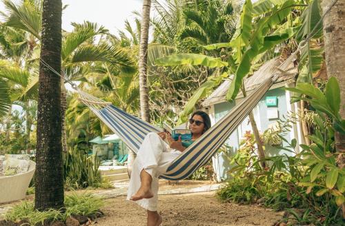 a man sitting in a hammock on the beach at Bleu de Toi Boutique Hotel in Grand Baie
