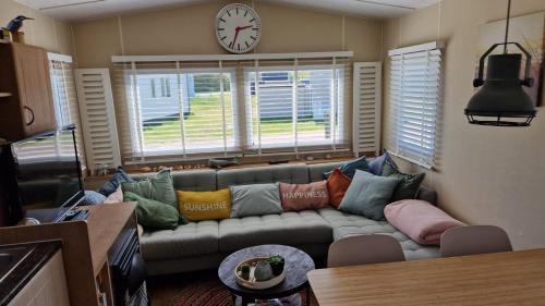 a living room with a couch and a clock on the wall at Stacaravan Duingras Ameland in Nes