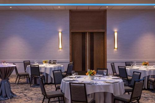 a room with tables and chairs with white tablecloths at Sheraton Charlotte Airport in Charlotte