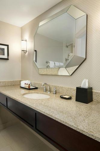 a bathroom with a sink and a large mirror at Sheraton Charlotte Airport in Charlotte