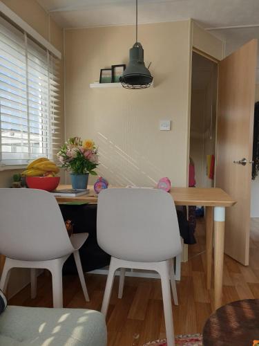 a kitchen with a table and two white chairs at Stacaravan Duingras Ameland in Nes