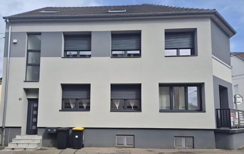 a white building with black windows at Appartement chaleureux pour 4 personnes in Diebling