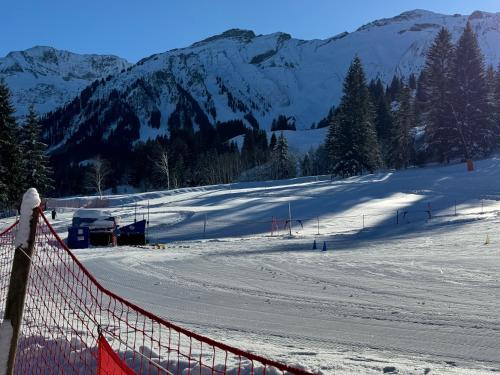a snow covered ski slope with a fence and mountains at Heimatli - moderne Ferienwohnung im Sörenberg in Sörenberg