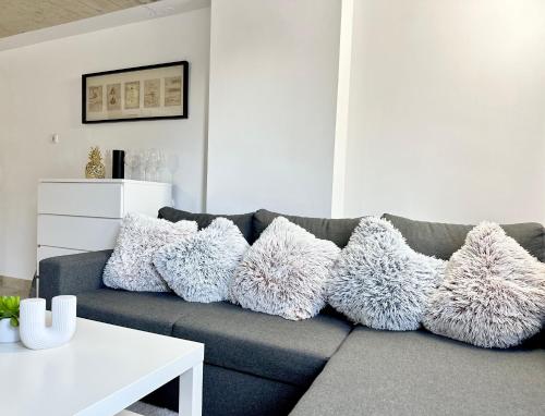 a living room with a gray couch with white pillows at Ground Floor Apt with a Pool and Terrace in Pesnica pri Mariboru