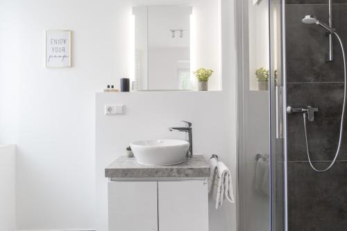 a white bathroom with a sink and a shower at living TIMELESS - Adler Apartments Sasbachwalden in Sasbachwalden