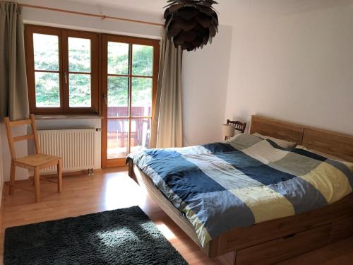 una camera da letto con un letto, una sedia e una finestra di Traumhafte Wohnung im Chiemgau a Schneizlreuth