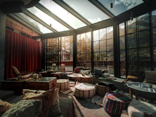 a large room with large windows and tables and couches at CERVO Mountain Resort in Zermatt