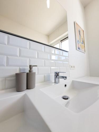 une salle de bain blanche avec un lavabo et un miroir dans l'établissement Le Charme - APPARTEMENT CENTRE VILLE, PROCHE DE LA PLAGE ET DU MARCHÉ, à Royan