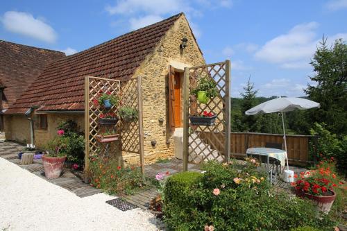 a small house with a garden with flowers and an umbrella at lO GORISSADO - La ferme du glandier in Saint-André-dʼAllas