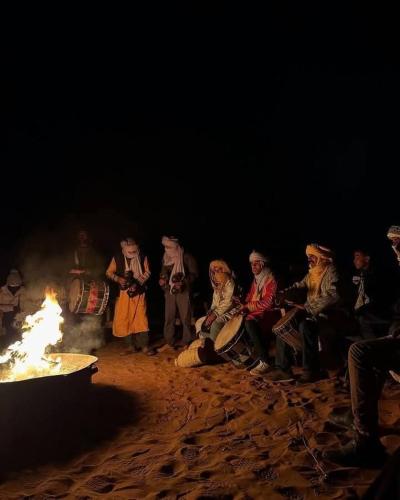 a group of people sitting around a fire at Camp trip Merzouga in Merzouga