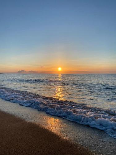 a sunset on a beach with the ocean at Camping Torre di Barisardo in Bari Sardo