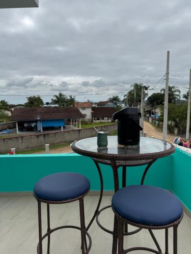 a table and two stools on a balcony at Suite 1- em Praia bonita hospedagem agora com ar condicionado in São Francisco do Sul