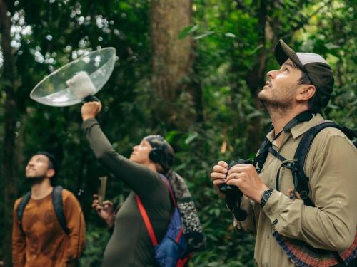 a group of people walking through a forest with a person holding a umbrella at Tambopata Research Center in Tambopata