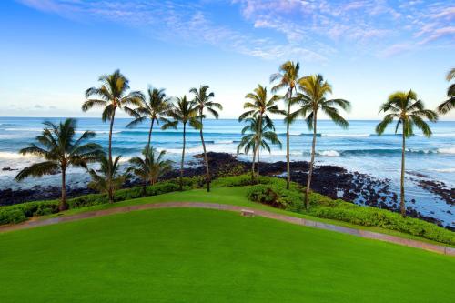 a golf course with palm trees and the ocean at Sheraton Kauai Resort in Koloa