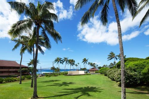a lawn with palm trees and the ocean in the background at Sheraton Kauai Resort in Koloa
