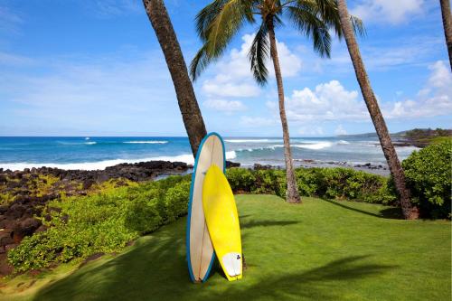 a yellow surfboard sitting on the grass next to palm trees at Sheraton Kauai Resort in Koloa