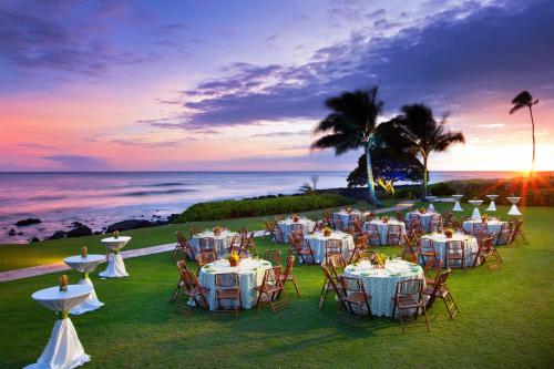 a group of tables and chairs with the ocean in the background at Sheraton Kauai Resort in Koloa