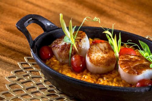 a black bowl of food with scallops on risotto at Sheraton Kauai Resort in Koloa