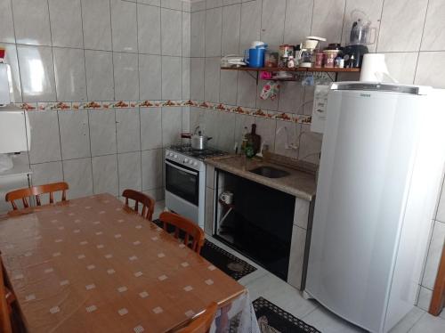 a small kitchen with a table and a refrigerator at Apartamento cem metros da praia in Matinhos