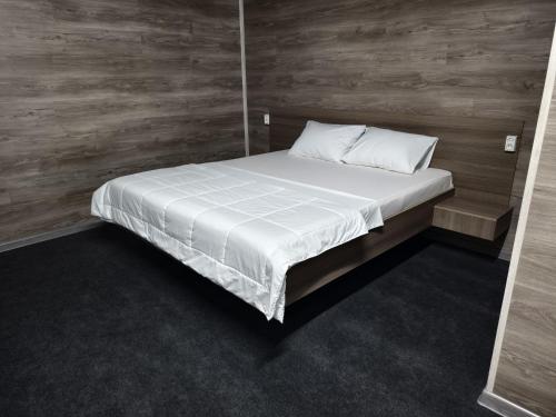 a bed with white sheets in a room with wooden walls at The Mini-hotel on Mukanov St in Almaty