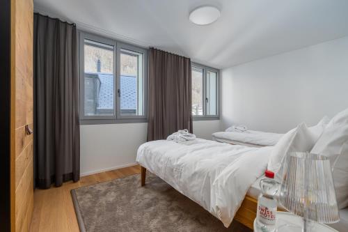 a bedroom with two beds and two windows at Swiss Hotel Apartments - Engelberg in Engelberg