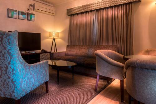 a hotel room with a couch and a tv at Protea Hotel by Marriott Lagos Kuramo Waters in Lagos