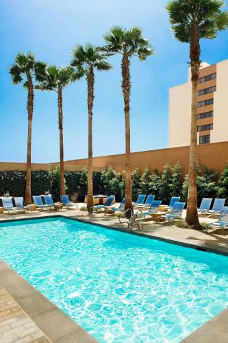 a swimming pool with palm trees and lounge chairs at Los Angeles Marriott Burbank Airport in Burbank