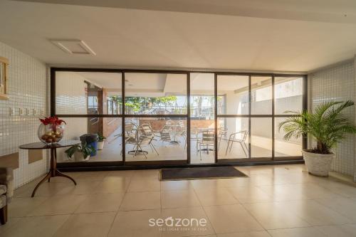 a room with glass doors and a table and chairs at Apto em cond quadra mar e c/ piscina HSS0007 in Tambaú