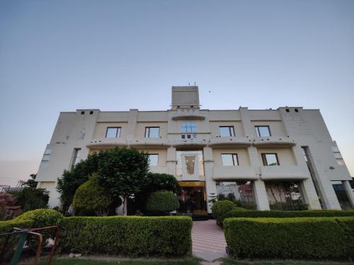 a large building with bushes in front of it at Hotel Vikramaditya in Gangānagar