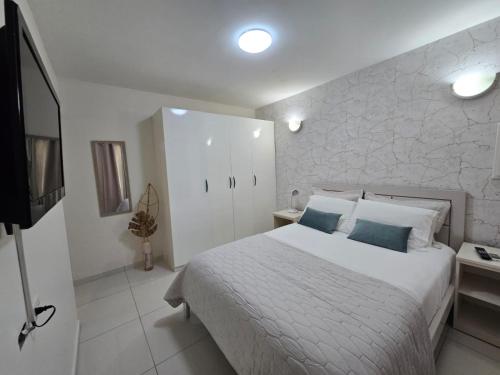 a bedroom with a white bed and a television at Bubali Residence in Palm-Eagle Beach