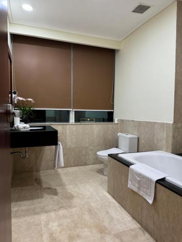 a bathroom with a tub and a toilet and a sink at Two Bedrooms, Two Bathrooms, Fully Furnished, Executive Apartment in Jakarta