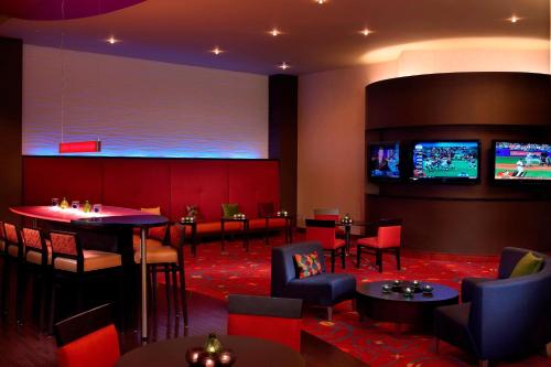 a bar with tables and chairs and a large screen at Marriott Kansas City Overland Park in Overland Park