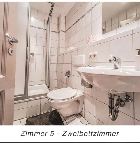 a white bathroom with a toilet and a sink at Hotel Weinstube am Markt in Gerolzhofen