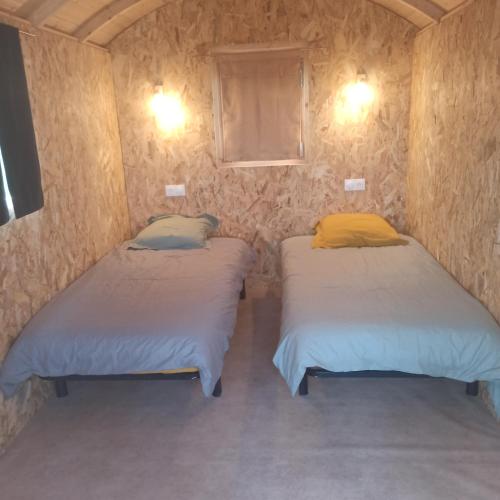 - deux lits jumeaux dans une petite chambre avec deux lumières dans l'établissement Maison 12 couchages, roulottes et piscine naturelle, à Laurenan