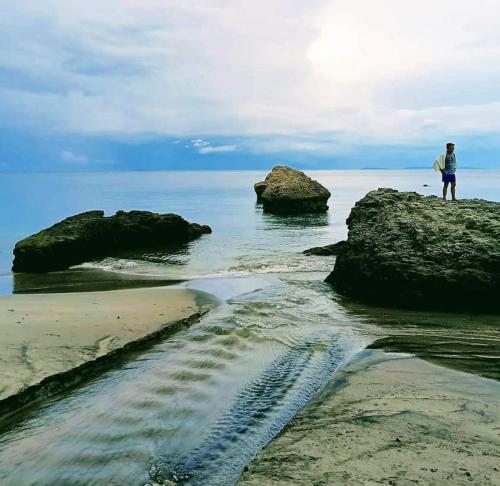 a person standing on a rock on the beach at Casa Vacanza Talaonga Ocean View Resort -Viajeros Booking Services in Sorsogon
