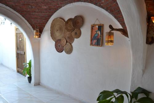 a hallway with a white wall with hats on it at Nebro Nubian Guest House - Adults Only in Aswan