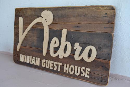 a sign for a houston guest house on a wall at Nebro Nubian Guest House - Adults Only in Aswan