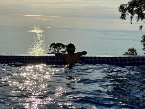 a man in a swimming pool looking out over the ocean at Villa Deluxe Kvariati in Kvariati