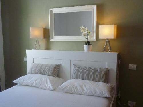 a bed with two pillows and a mirror and two lamps at Casa Paola in Tías