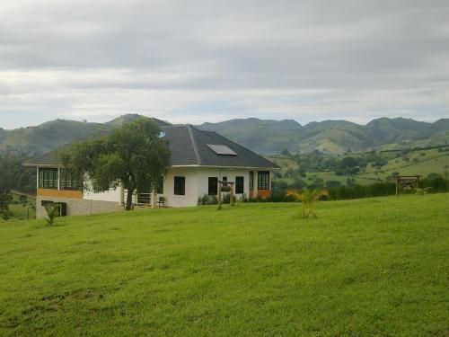 a house in a field with mountains in the background at The Crested Crane Bwindi Hotel in Rugando