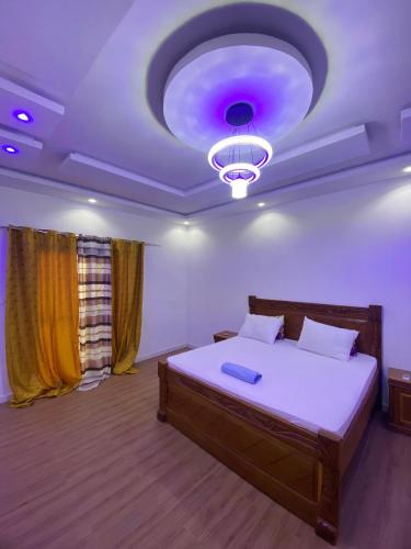 a bedroom with a large bed with a purple ceiling at Camara's Home in Sali Nianiaral