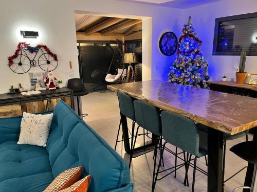un salon avec un canapé bleu et un sapin de Noël dans l'établissement Maison Cosy à la montagne, à Châtillon-de-Michaille